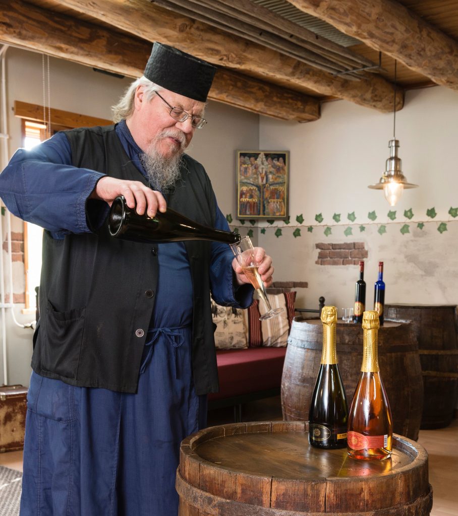 Kuva miehestä, joka kaataa viiniä lasiin